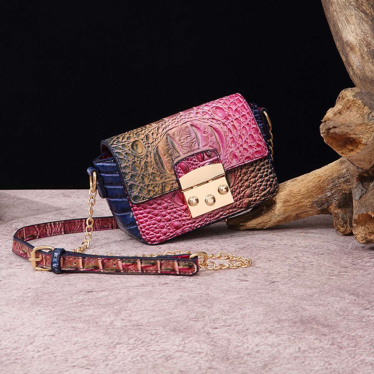 Multicolor one-shoulder crossbody bag with pink and dark blue panels, gold-tone clasp, chain strap.
