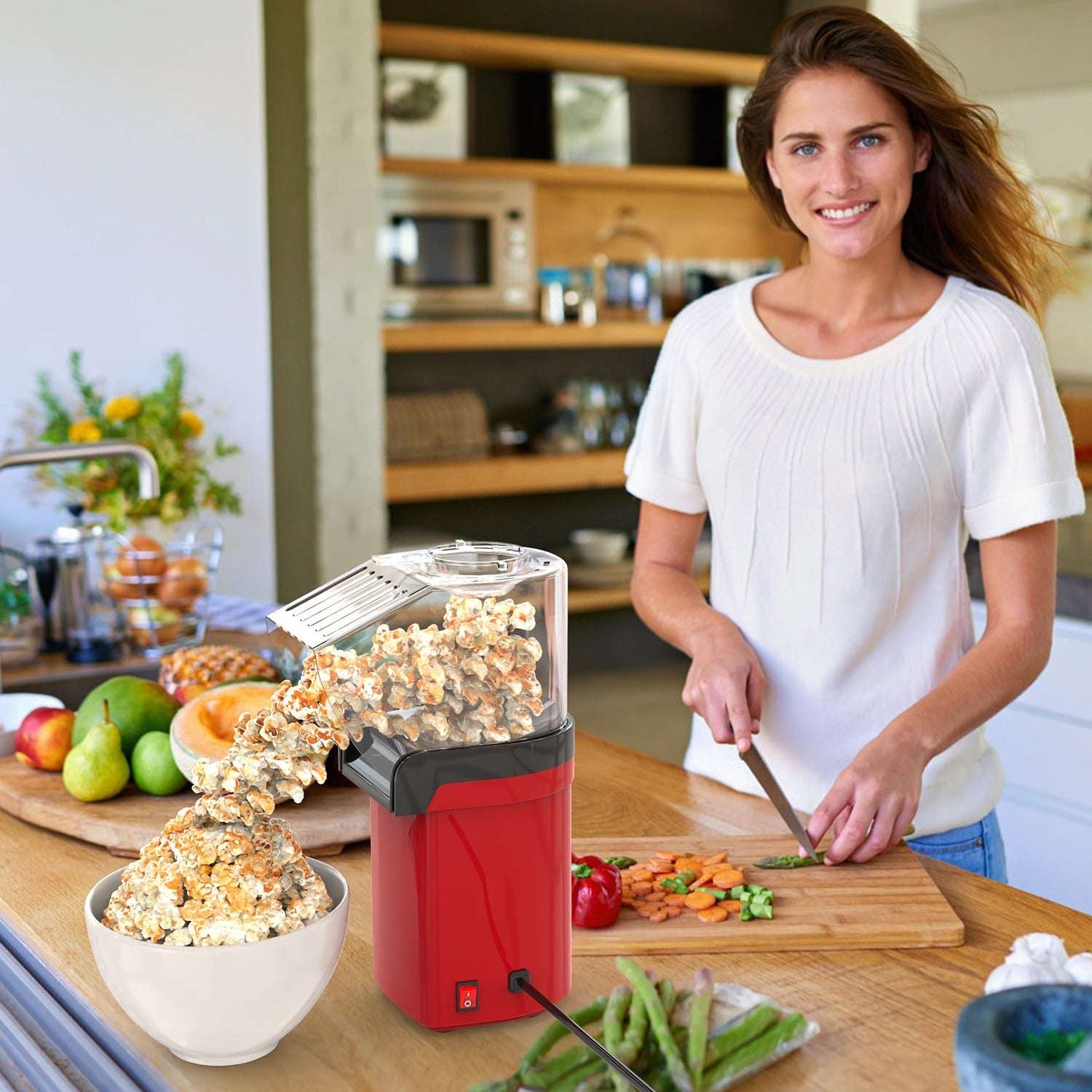 Woman in a kitchen with a popcorn maker and fresh vegetables