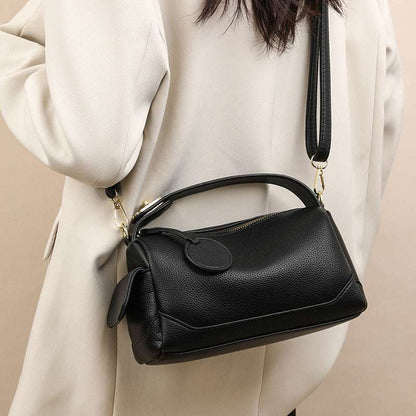 Black leather pillow bag with rounded front, front flap, and adjustable crossbody strap