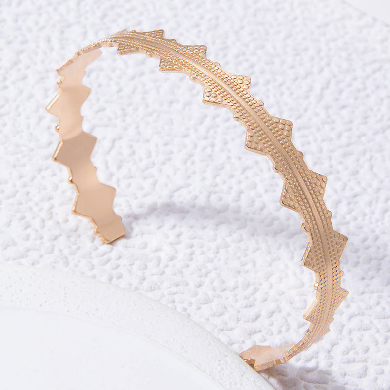 Geometric openwork letter bow bracelet in gold-tone metal, cuff-style
