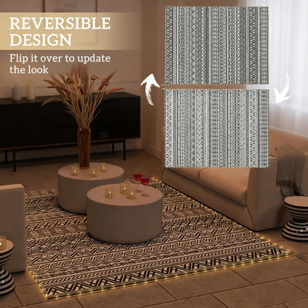Reversible outdoor rug with dark geometric pattern and gold-edged border on tile floor