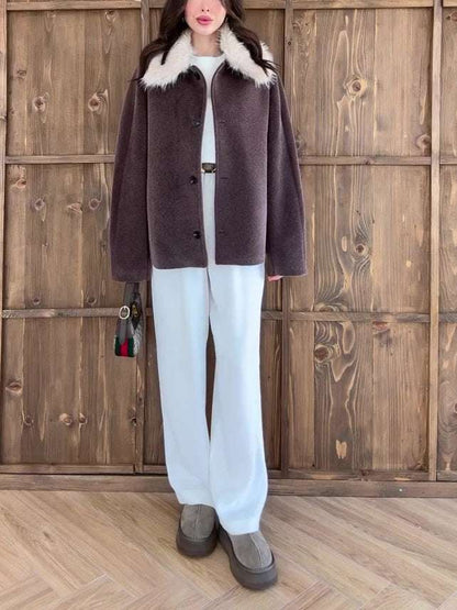Person wearing a brown coat with white fur collar against a wooden background