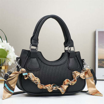 Black braided chain crossbody handbag with top handles, structured hobo shape.