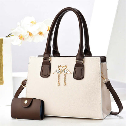 White large crossbody tote bag with brown handles, front heart charm, and side pouch