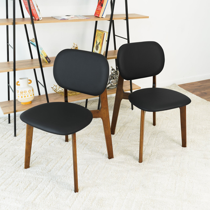 Set of 2 black leather side chairs angled view, rounded seat and back, wood legs