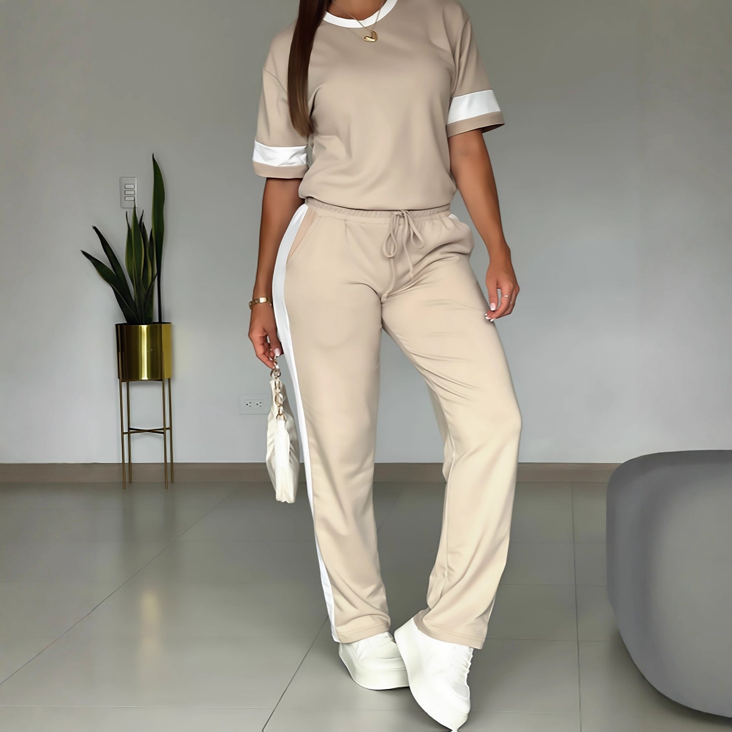 A woman in a premium beige casual sportswear suit featuring a zip-up hoodie and matching joggers with stylish contrast piping.