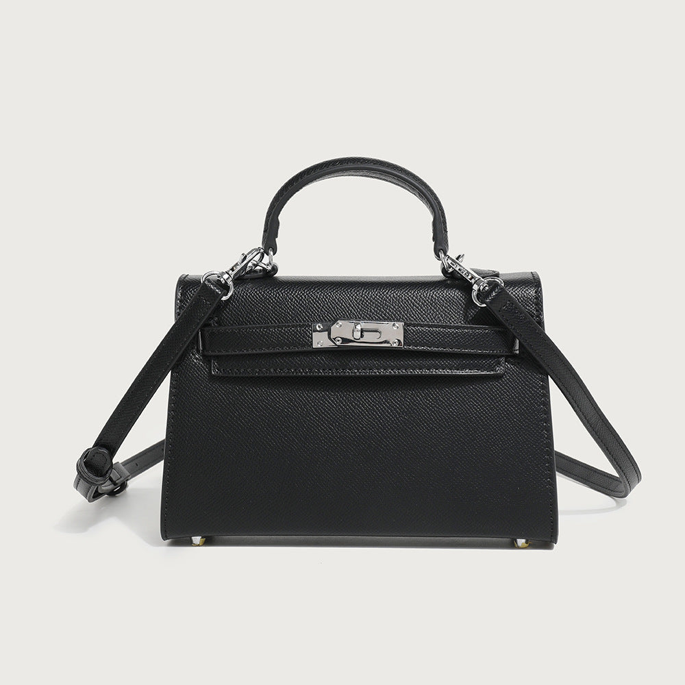 Black mini handbag with top handle, flap front, and crossbody strap; gold feet