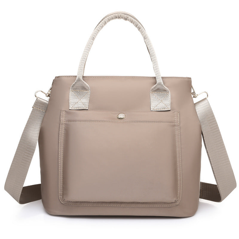 Taupe fabric handbag with light straps, front pocket, and top button closure