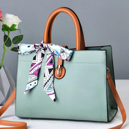 Large mint crossbody tote with brown handles, patterned ribbon scarf, and metal clasp