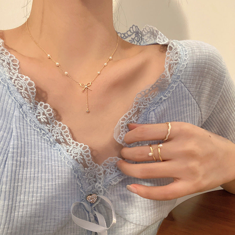 Gold-tone pearl necklace with cross-like charm and small bead drops