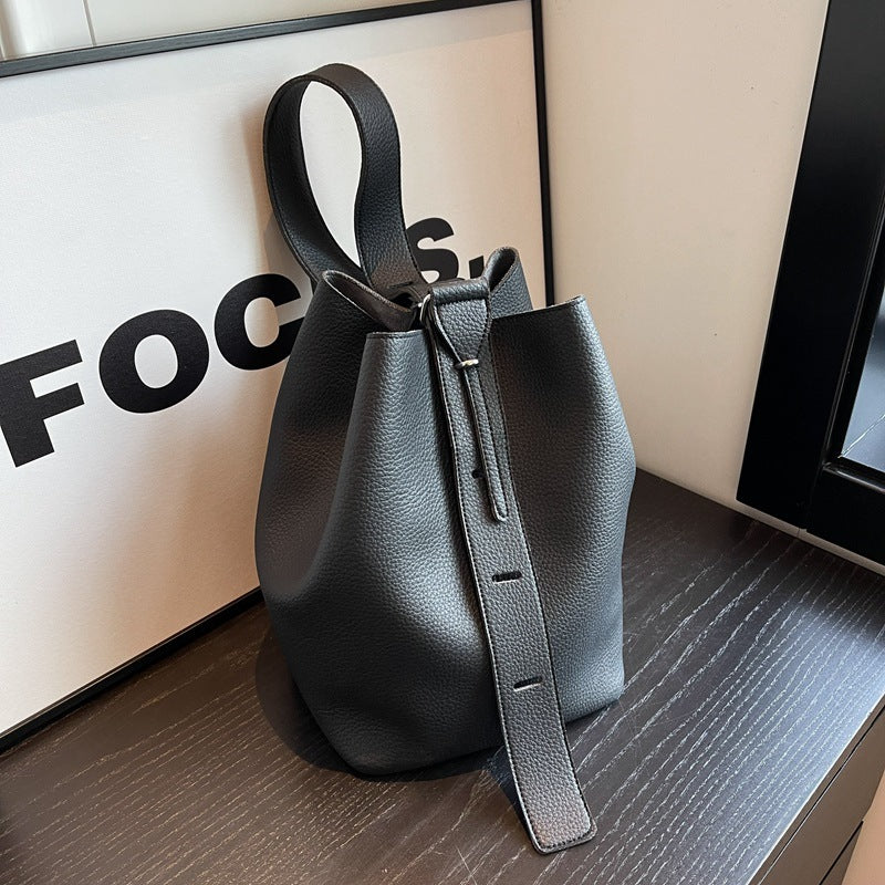 Pebble-grain bucket bag in black with drawstring top and adjustable strap