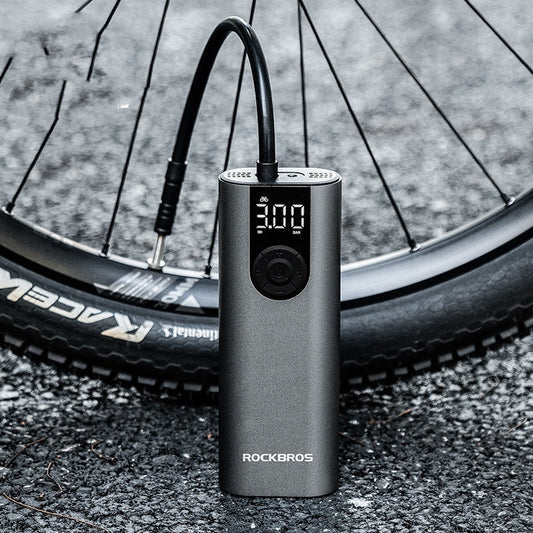 Bicycle tire being pumped up by a ROCKBROS air pump on a road.