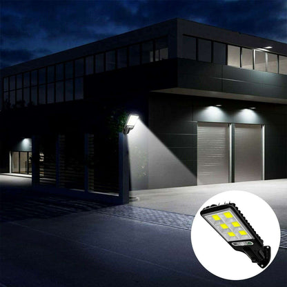 Black solar LED street light casting light along a building walkway at night