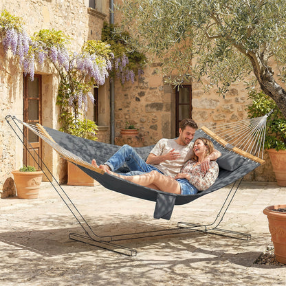 Gray two-person outdoor hammock with pillow, two adults reclining on the padded bed