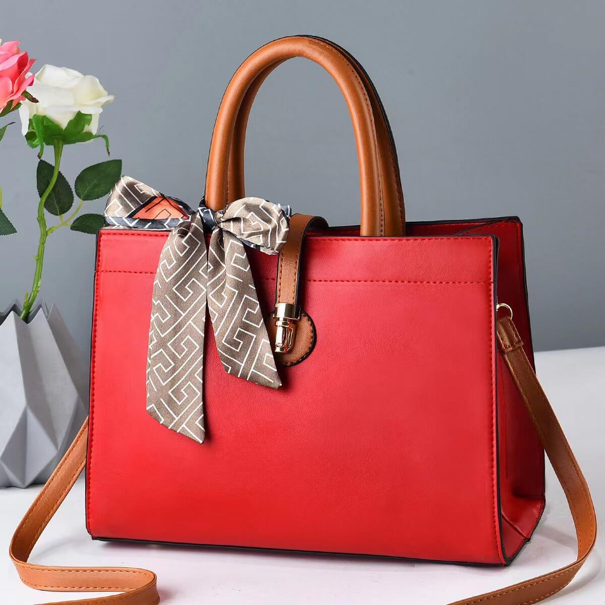 Large red crossbody tote with brown handles, gray patterned scarf tie, and metal clasp