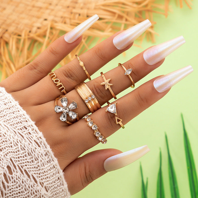 Gold-tone crystal ring set with star and heart-like charms, stacked on hand