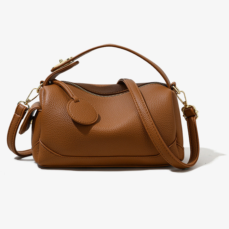 Tan leather pillow bag with front flap, top handle, and crossbody strap, gold hardware