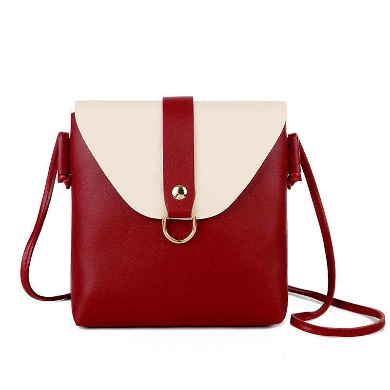 Red messenger bag with white top flap, gold ring snap, and crossbody strap