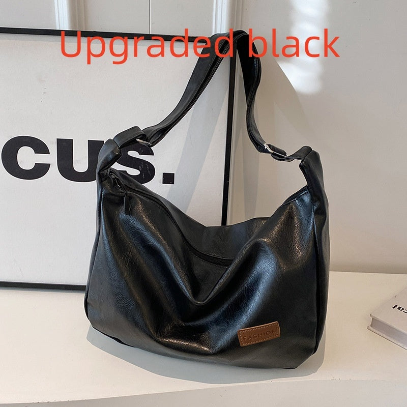 Black hobo shoulder bag with long strap, logo patch, and hanging keychain charm