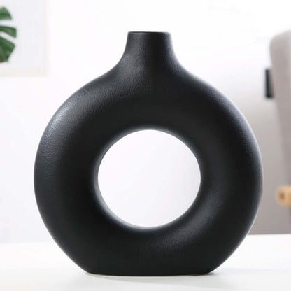 Black ceramic vase with round cutout center, rounded sculptural shape