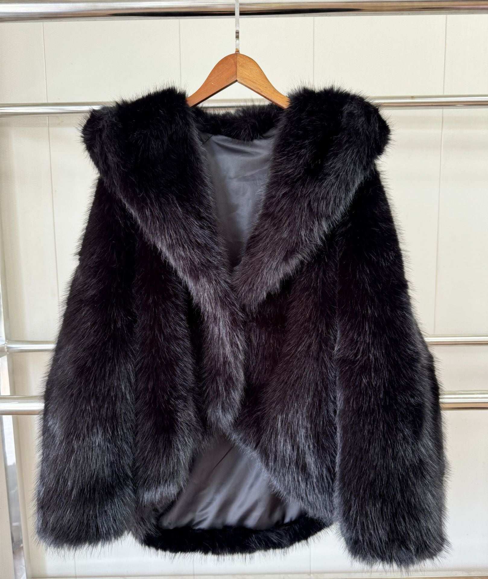 Black faux fur hooded coat hanging, open front with textured sleeves.