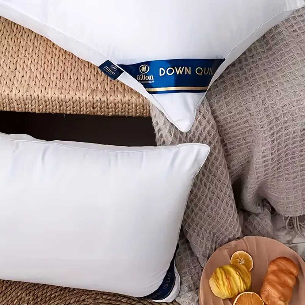 White down-style bed pillows with blue label and smooth microfiber cover
