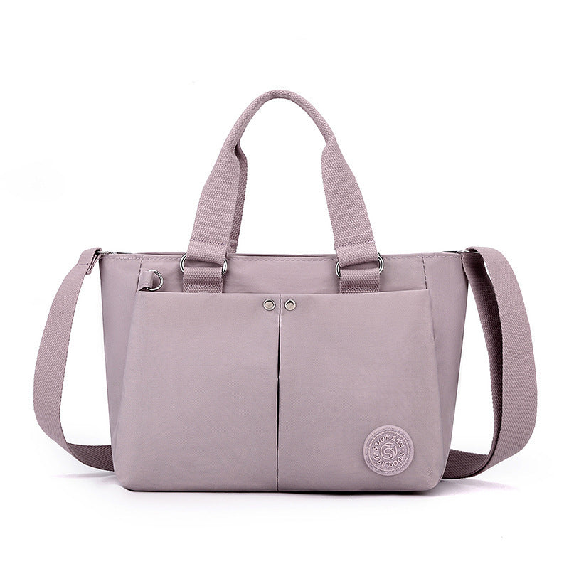 Waterproof shoulder bag, light purple with two handles and round logo patch