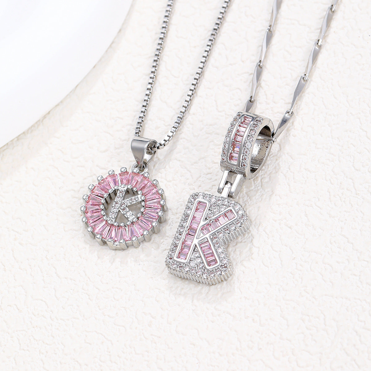 Silver pendant necklace set with pink crystal flower charm and letter pendant, overlapping angles