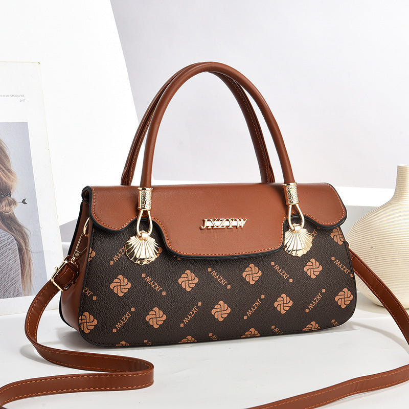 Women’s crossbody handbag in dark brown with letter-style print and tassel charm accents.