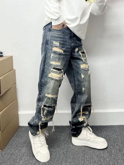 Light blue men’s ripped patch jeans with layered rips and patches at thighs and knees