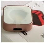 Red wireless magnetic watch charger resting on a surface, showing top panel and ports