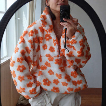 Person wearing a white fleece jacket with orange floral patterns, taking a mirror selfie.