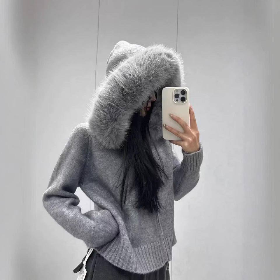 Person wearing a gray hoodie with a fur-lined hood, taking a mirror selfie.