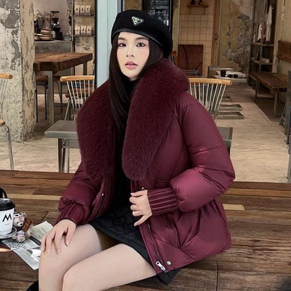 Woman wearing a burgundy coat with fur collar sitting in a cafe.