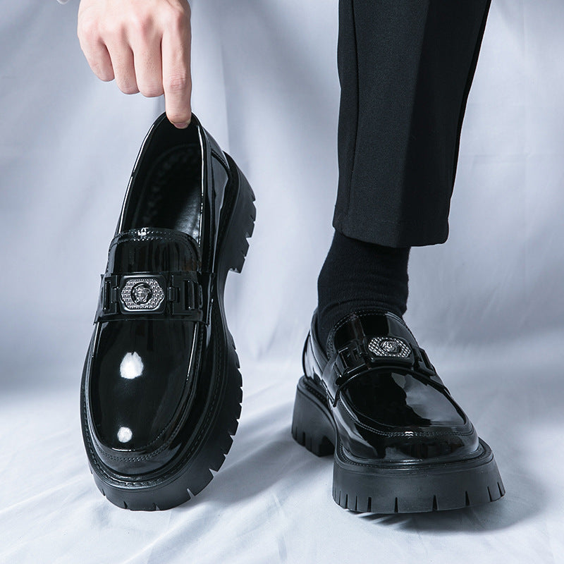 Glossy black platform loafer with buckle strap and decorative emblem at the front