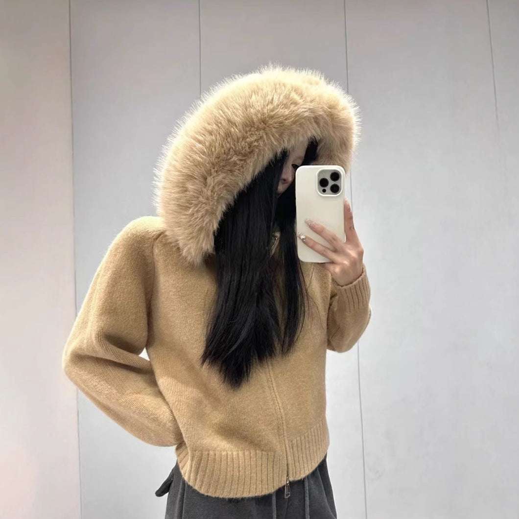 Person wearing a beige hoodie with a fur-lined hood, taking a mirror selfie.