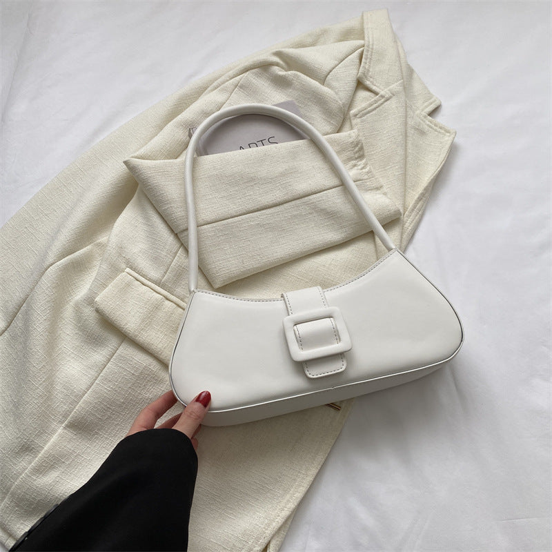 Small square crossbody bag, white, curved flap with buckle strap and short top handle.