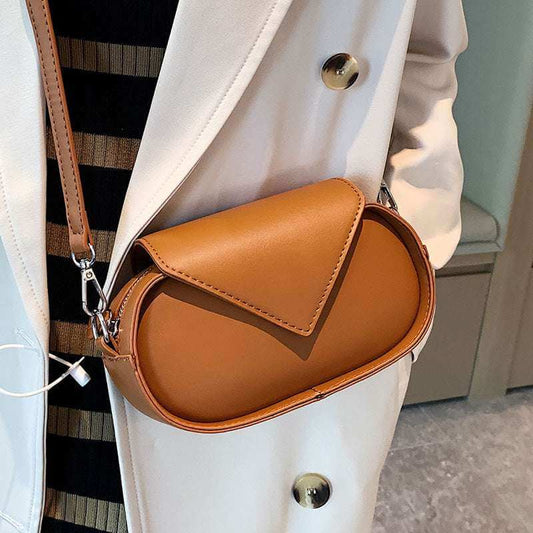 Tan shoulder bag with flap top, stitched trim, and metal crossbody hardware