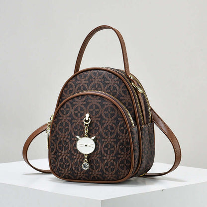 Brown patterned mini shoulder handbag with top handle and dangling heart charm
