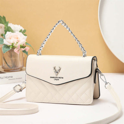 Quilted mini crossbody bag in white with silver chain strap and front flap with snap.