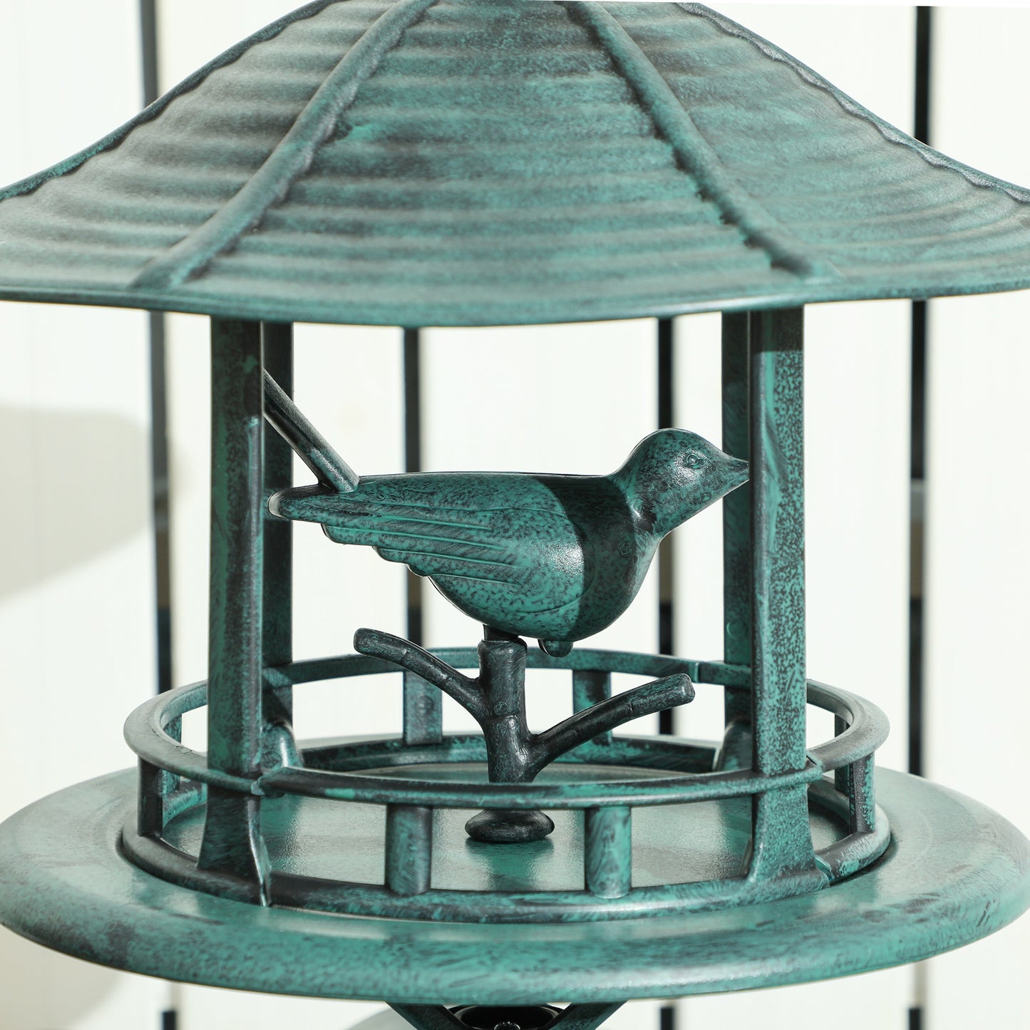 Antique green bird feeder with small roof and circular tray, bird perched