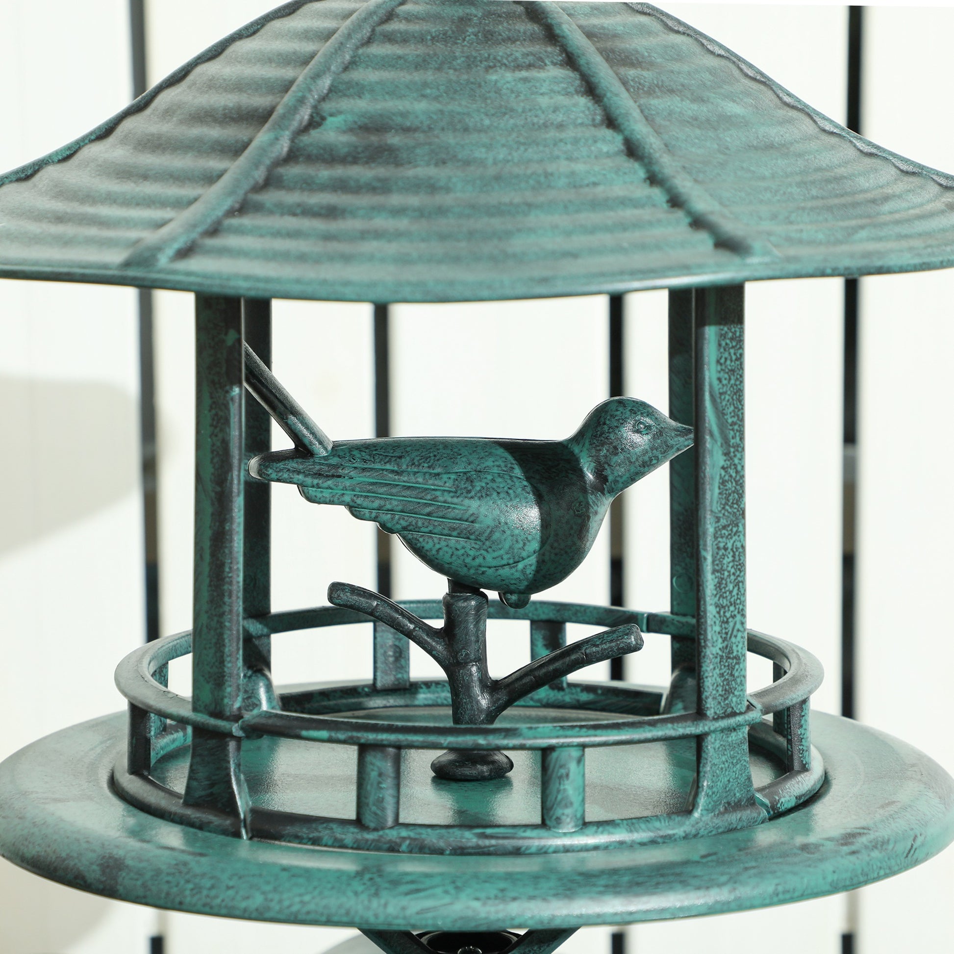 Antique green bird feeder with small roof and circular tray, bird perched