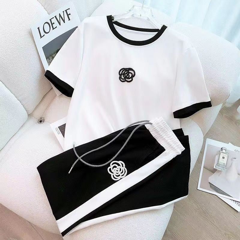 Women's two-piece set: white tee with black trim and logo, paired with black wide-leg pants