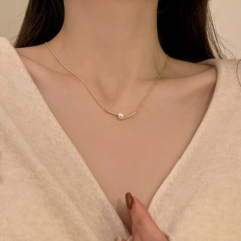Gold-tone pearl bead necklace with a single small pearl at the center
