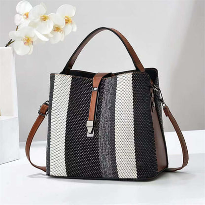 Large crossbody handbag in dark fabric with white vertical stripes and brown handles