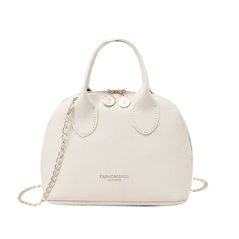 White dome handbag with chain strap, curved handle tabs, and gold-tone clasps