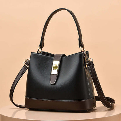 Black tote handbag with curved top handles, shoulder strap, and gold clasp