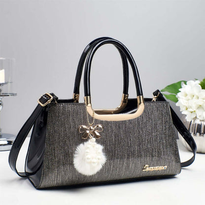 Structured glitter tote handbag with black handles and white pom-pom charm