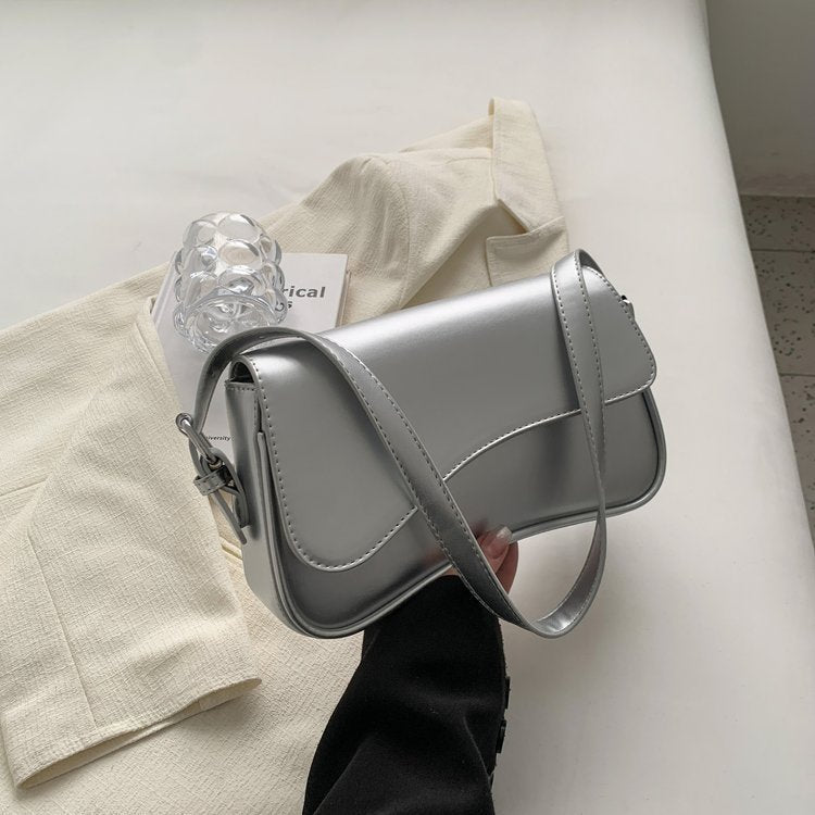 Silver shoulder bag with flap and magnetic buckle, curved seams, crossbody strap