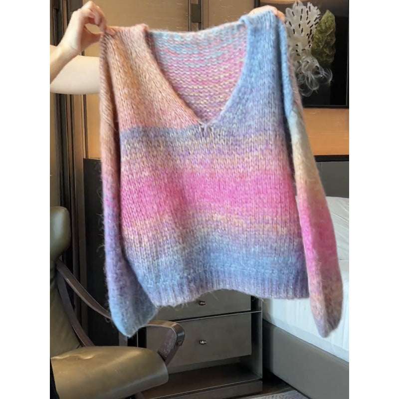 Multicolored knitted sweater held up against a neutral background